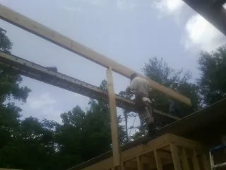 Carpenter setting a ridge beam over a new addition frame — Ice Dam Removal by Roofing Brothers in Ambrose