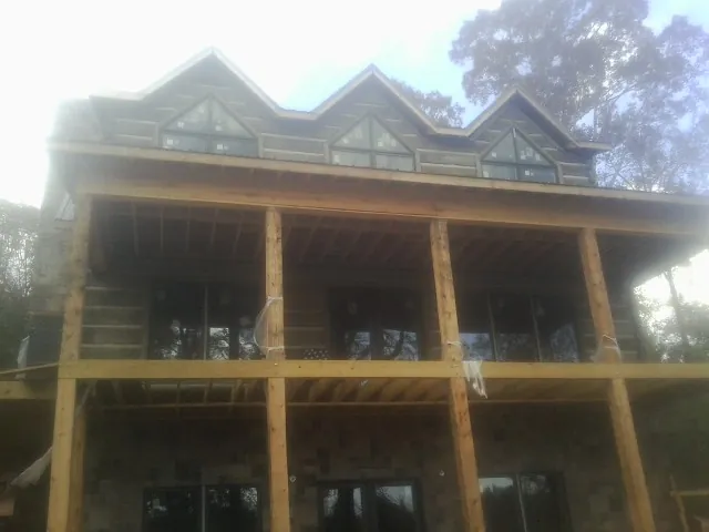 Dormers and porch framing on a large log home under construction — Roof Coating work by our crew in Ambrose