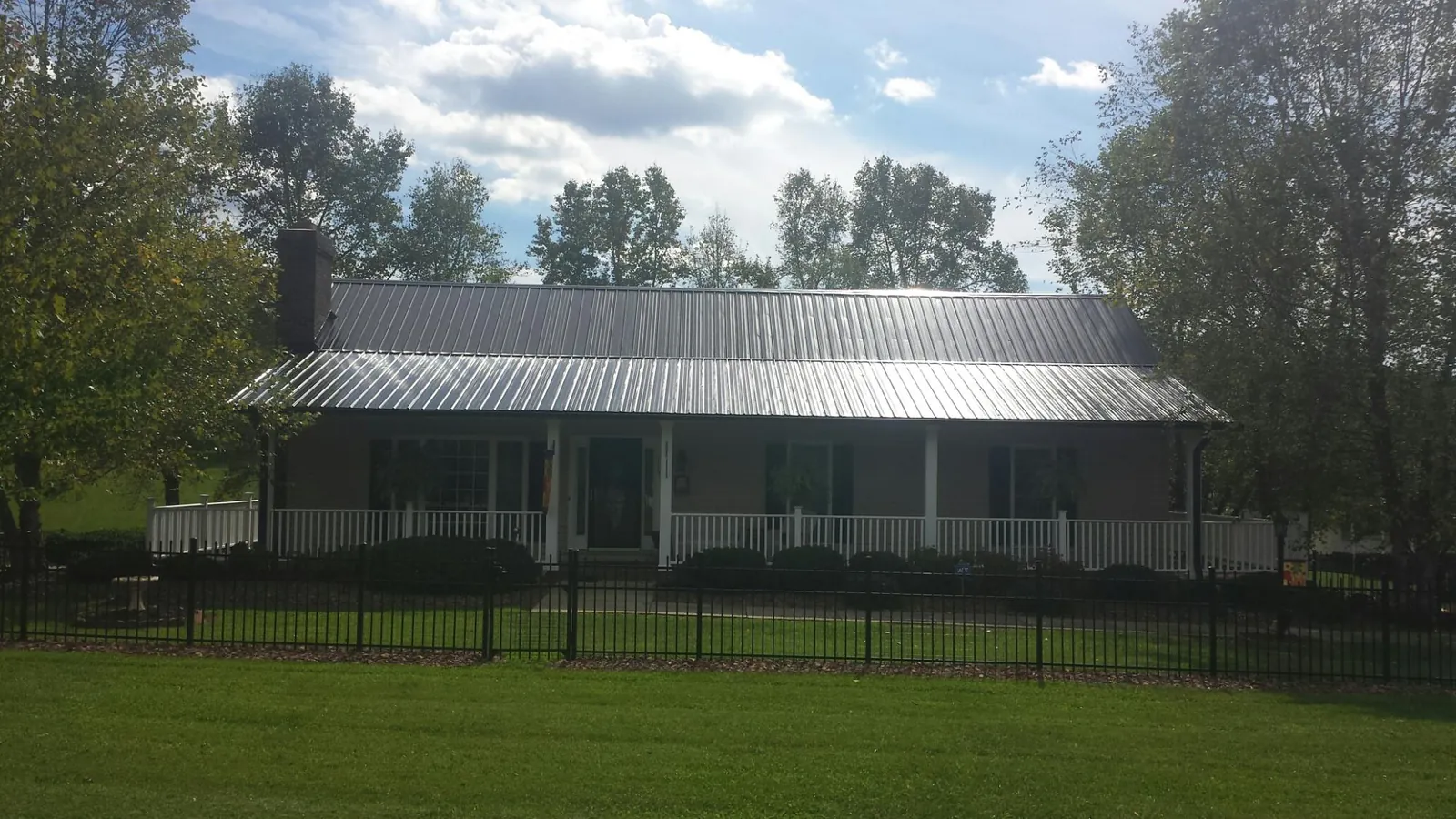 Gray metal roof on a brick ranch with a full width front porch — Gutter Guard Installation work by our crew in Ambrose