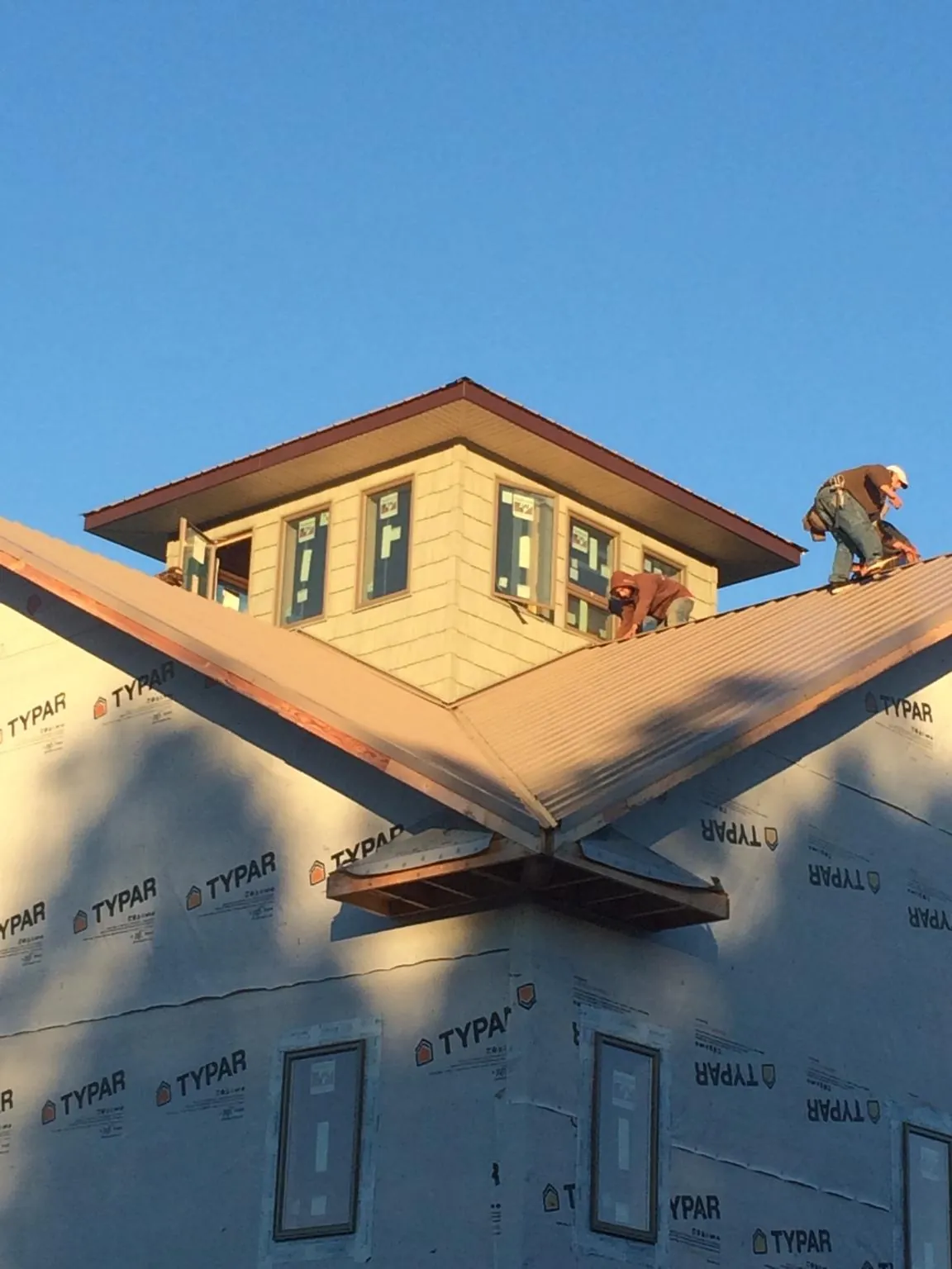 Roofers working around a rooftop cupola on a new metal roof at sunset — Roof Waterproofing in Ambrose by Roofing Brothers